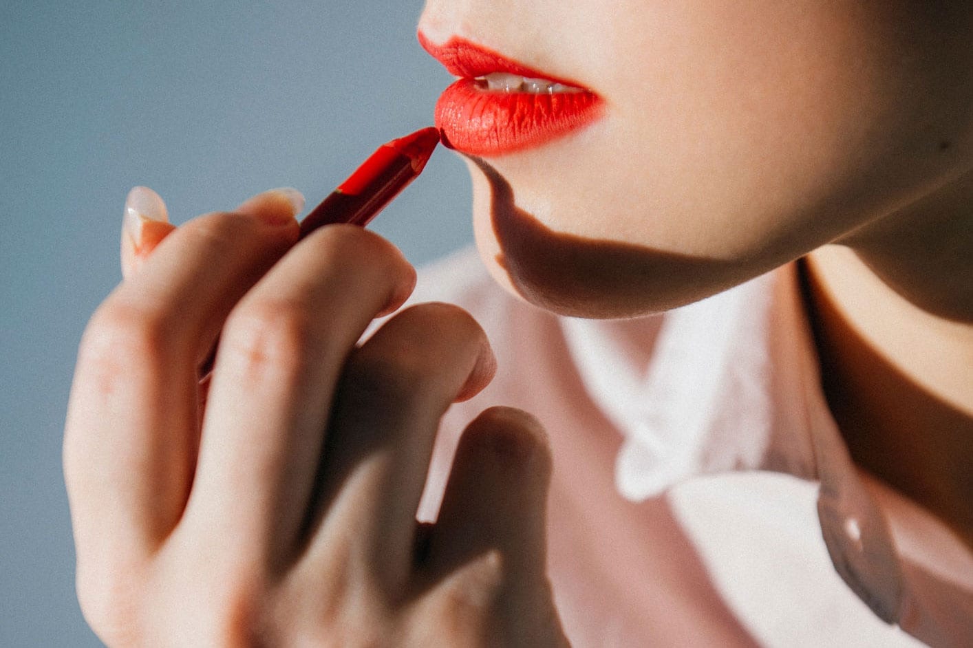 A woman applies a lip crayon.
