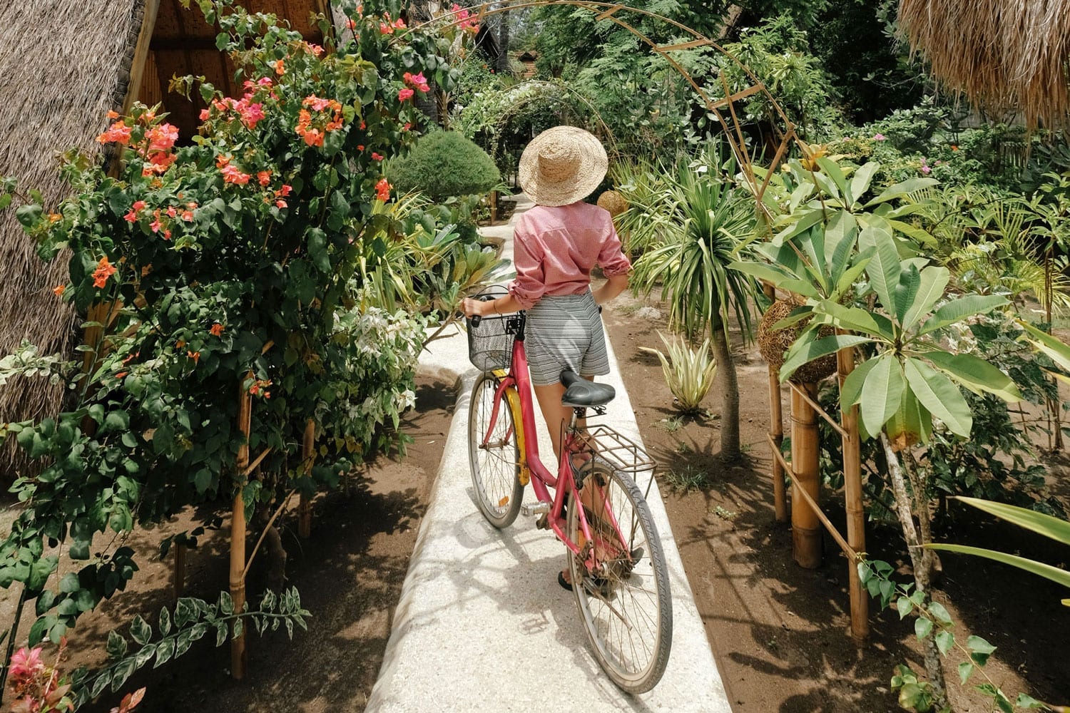 A woman with a bicycle stands near a villa.