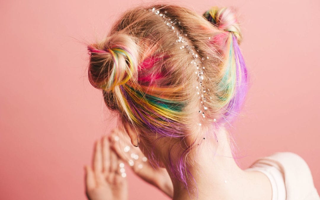 A photo of a woman with colorful hair and glitter stars on her hairline.