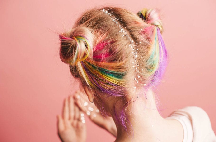 A photo of a woman with colorful hair and glitter stars on her hairline.