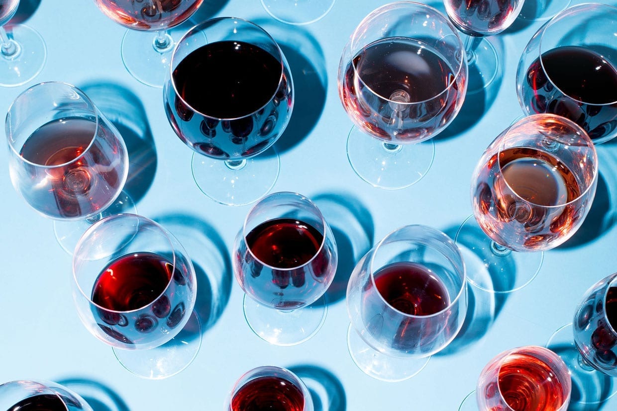 A photo of different wine glasses on a blue background.