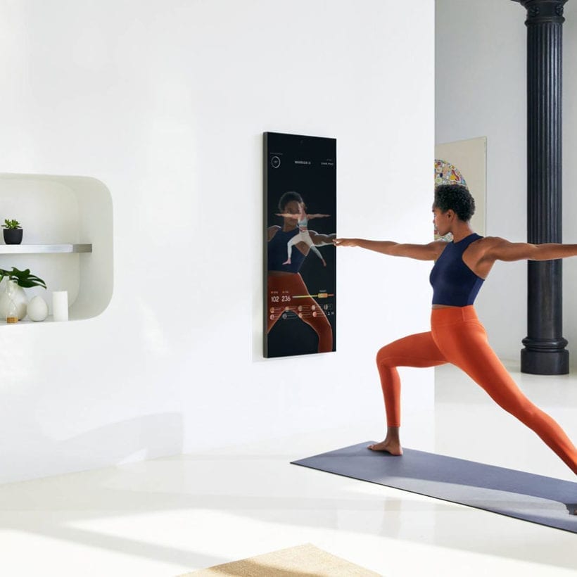 A photo of a woman using Mirror to exercise.