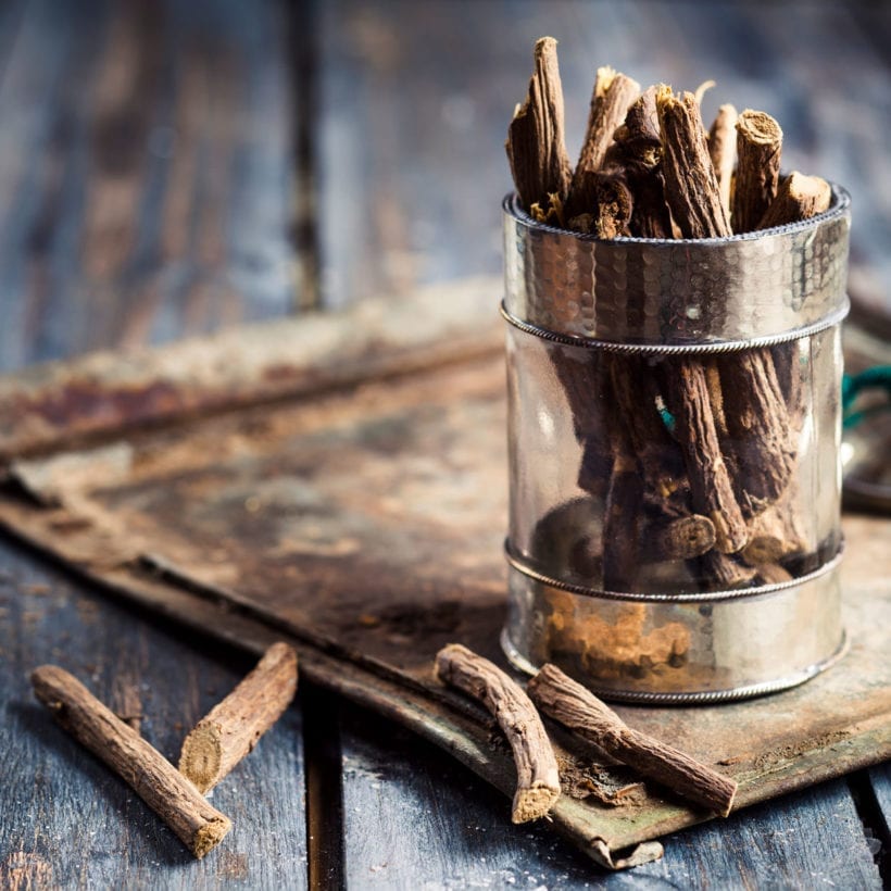 Glass of licorice root on a wooden table.