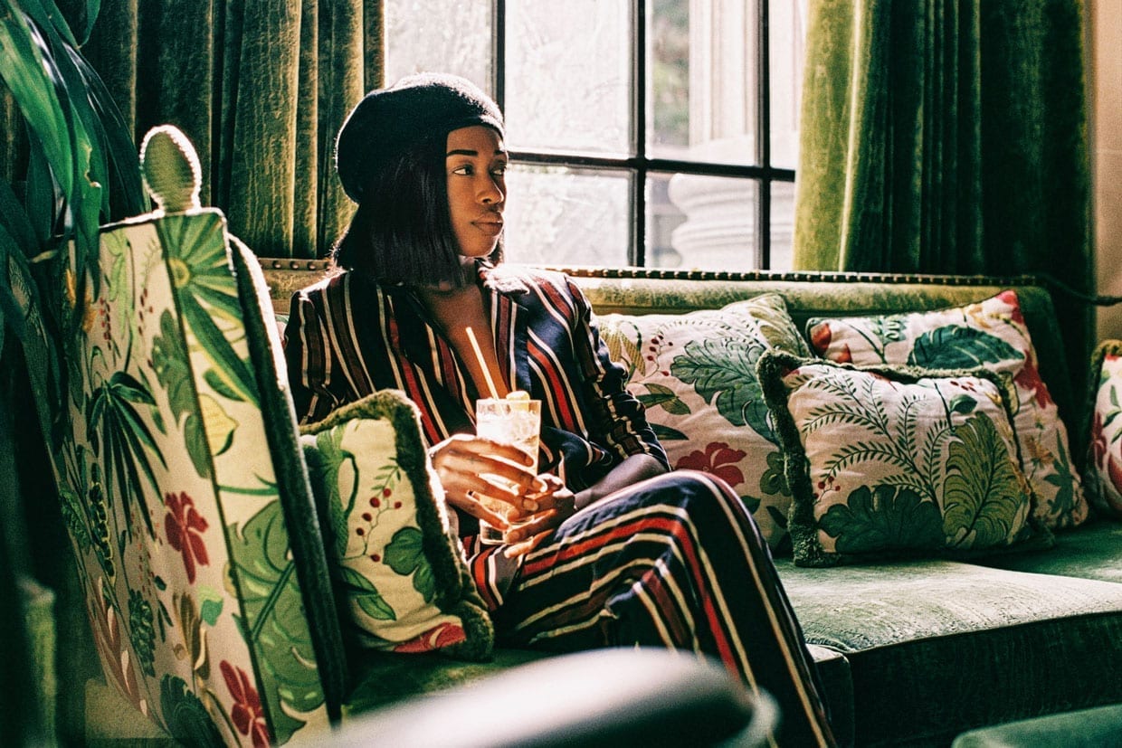 A photo of a woman sitting on a couch holding a drink.