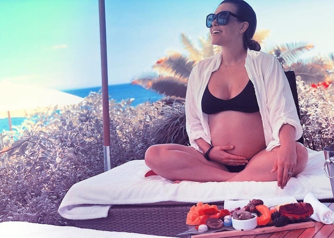 Rachel Platten sits on a chair in a bikini holding her baby bump in this photo from Platten's Instagram account.
