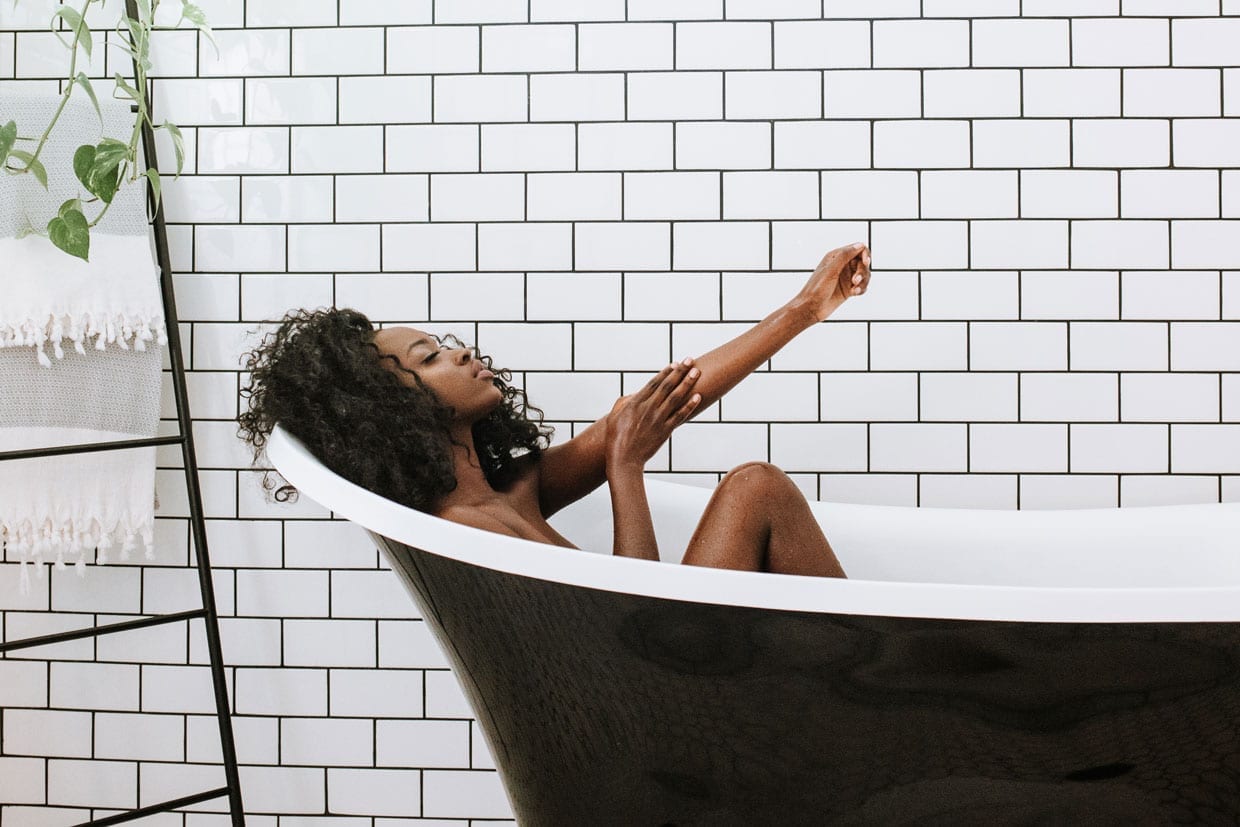 A black woman relaxes in a tub.