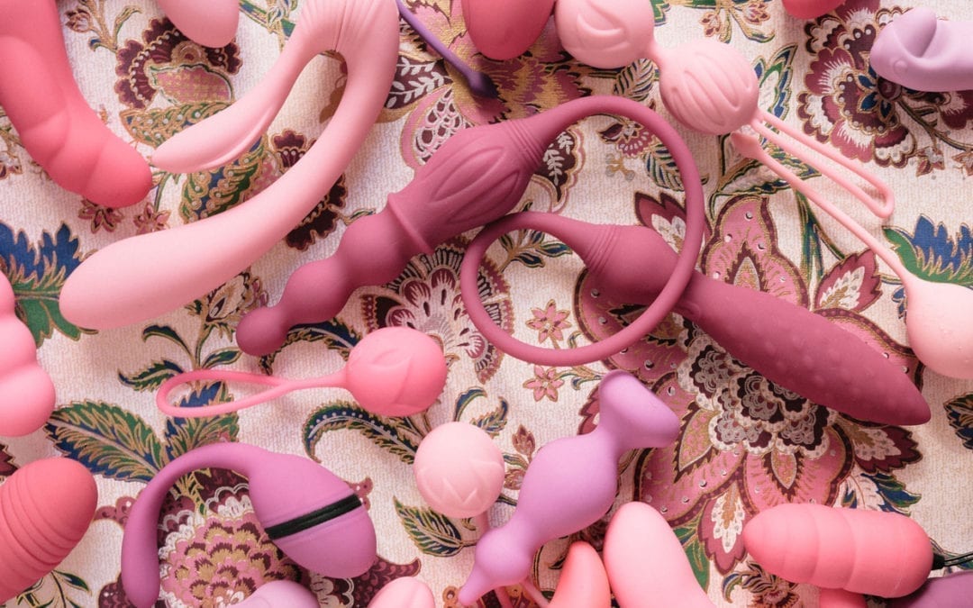 A variety of pink sex toys on a flower paper background.