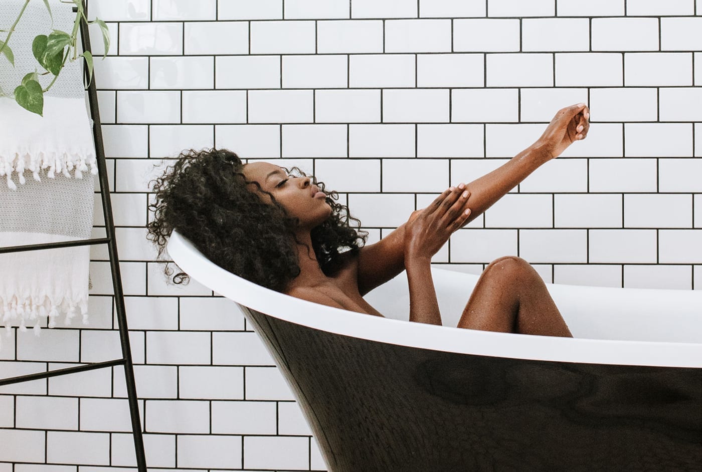 A black woman relaxes in a tub.