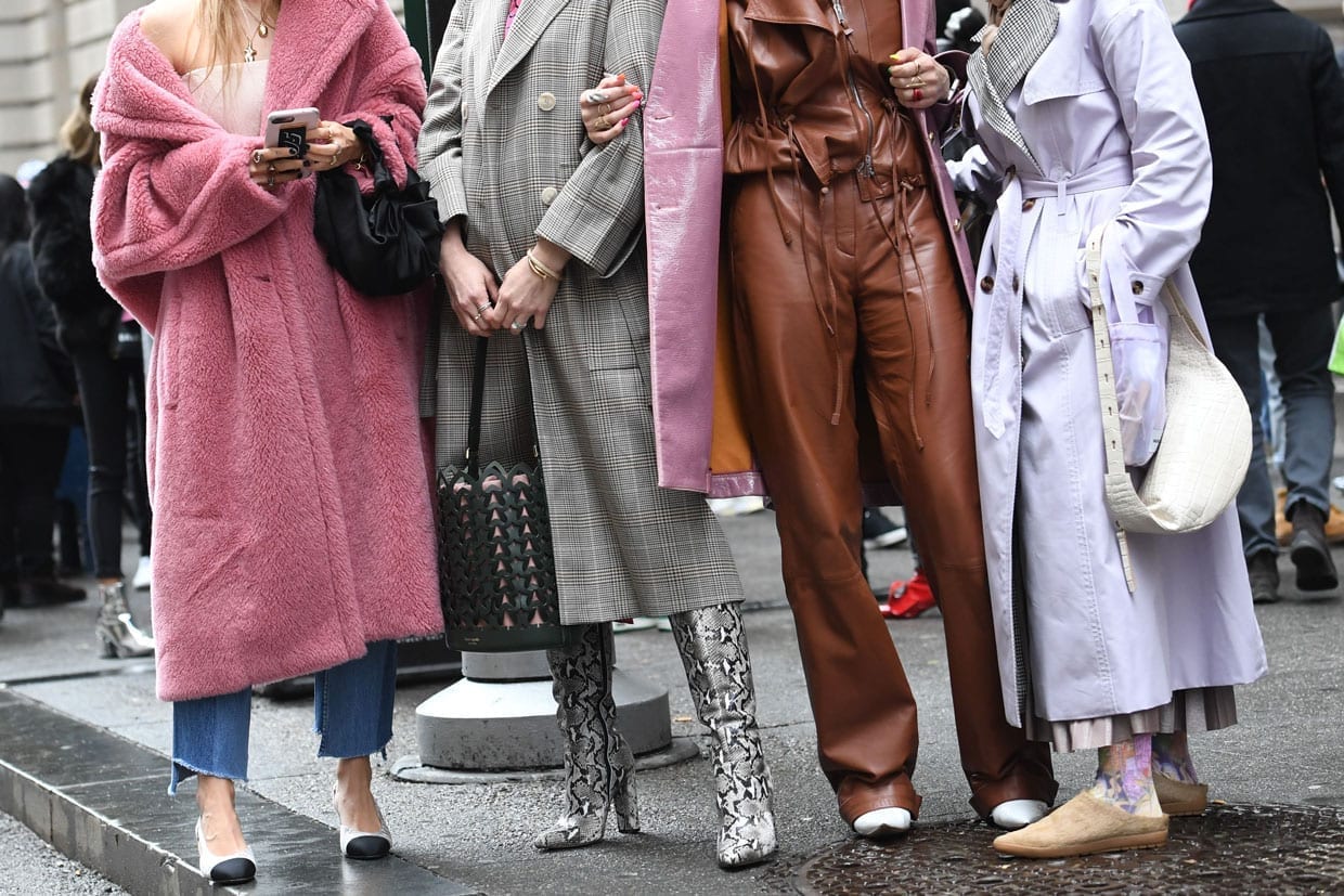 Four women in colorful coats standing on the sidewalk in New York City.