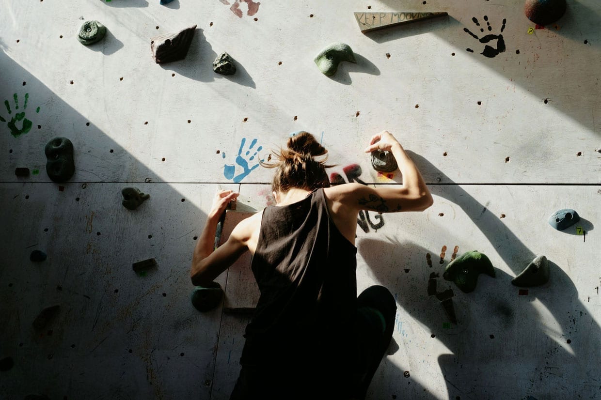 Young woman doing indoor climbing on the training wall.