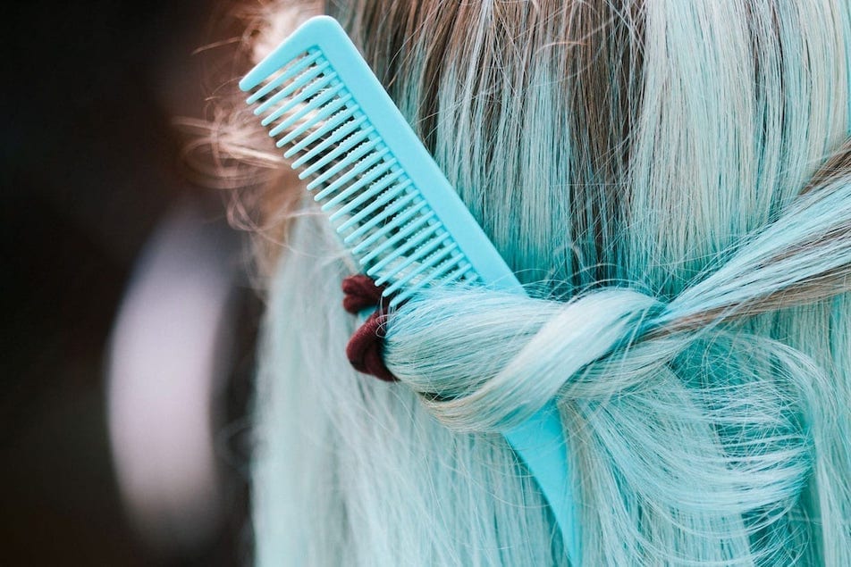 A woman with blue hair with comb stuck in it.