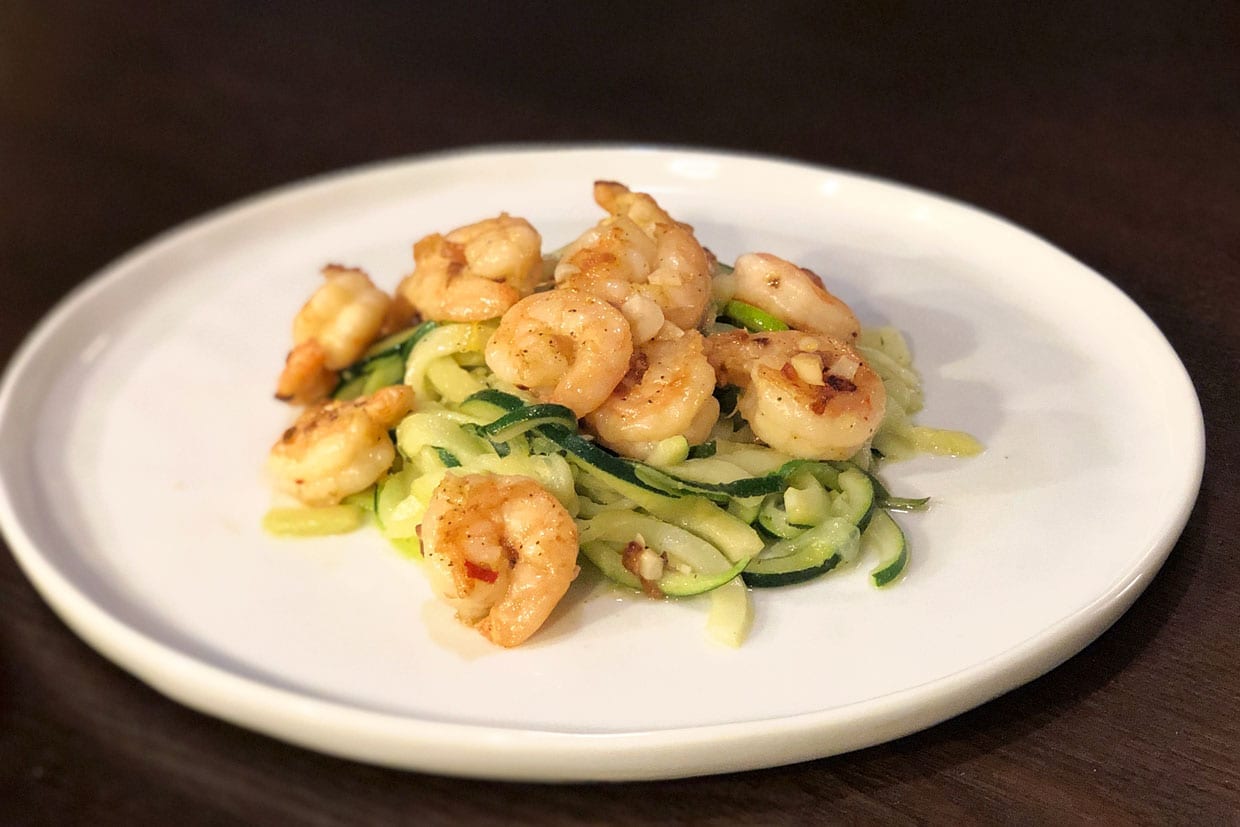 Shrimp Scampi on a white plate on a wood table.