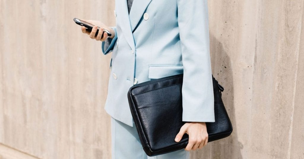 A woman in a light blue suit looks at her phone.