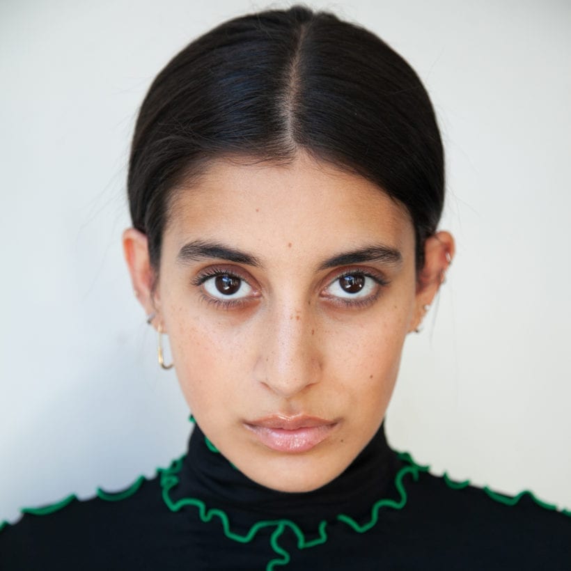 A close up of a South Asian woman's face looking straight at the camera.