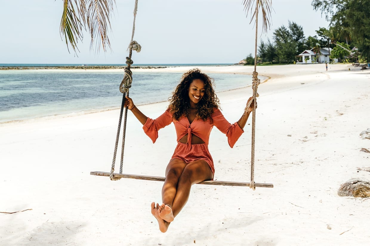 A woman on a swing on the beach.