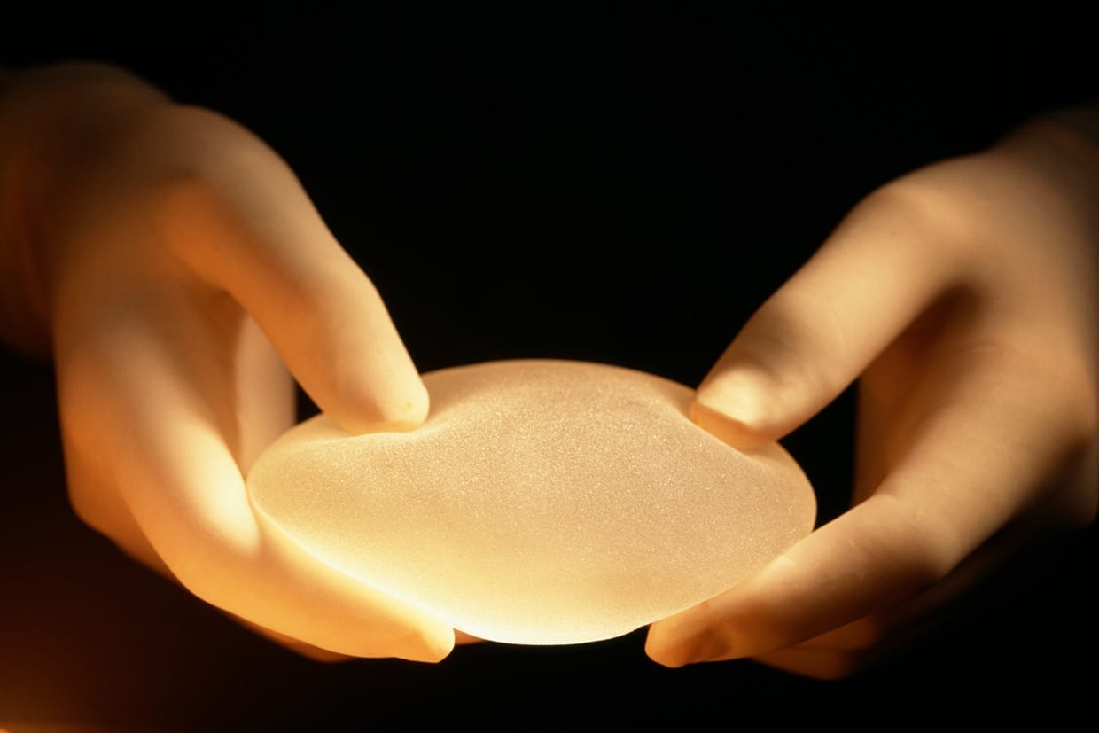 Surgeon holding a cosmetic breast implant.