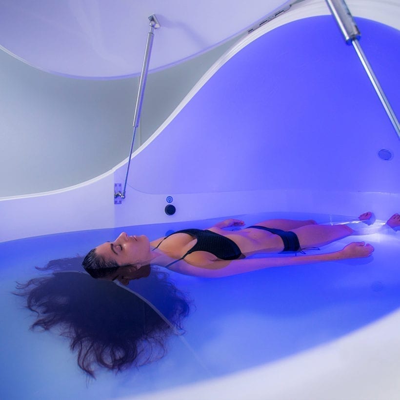 A woman floating in water in a sensory deprivation pod.