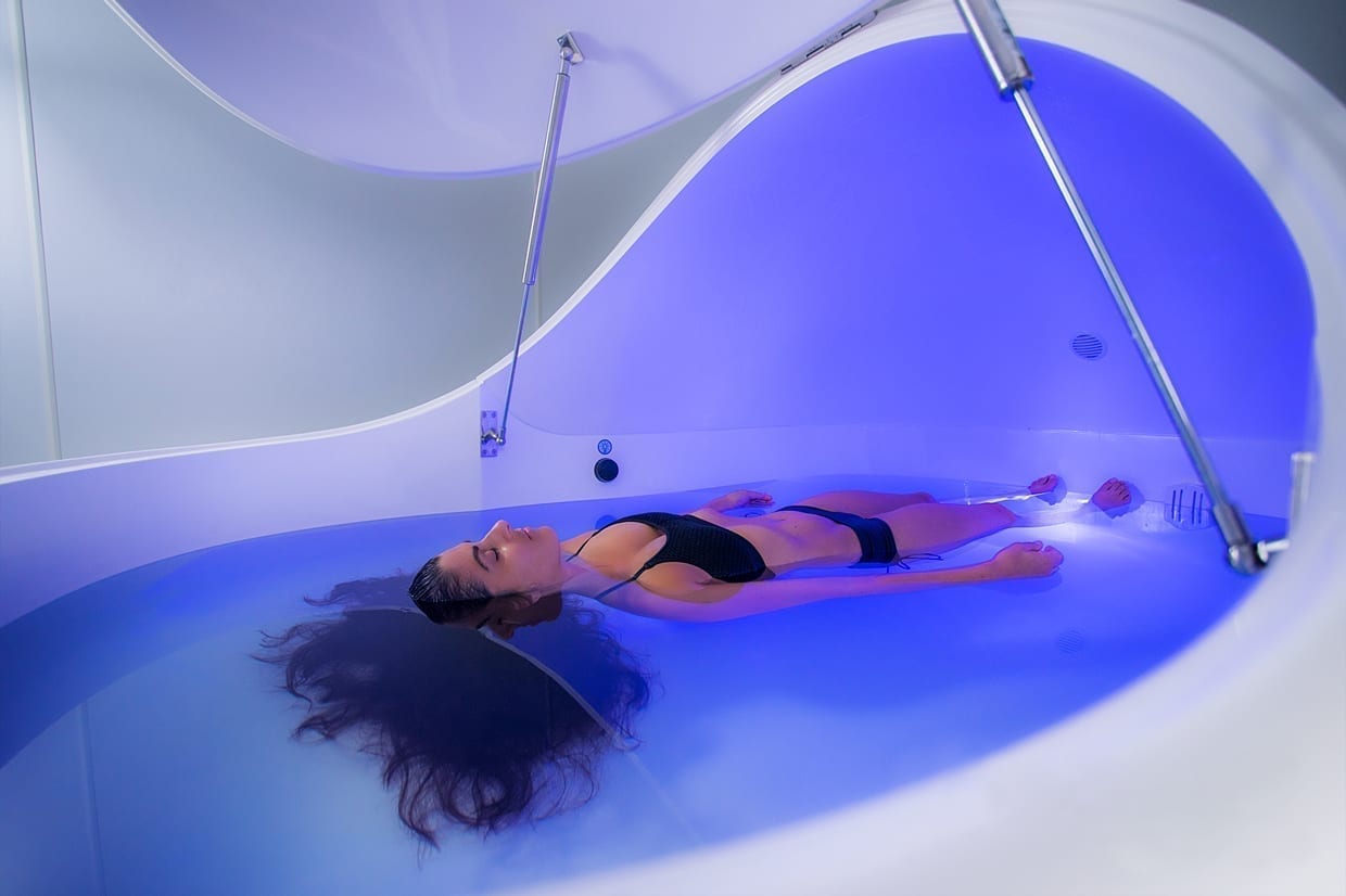 A woman floating in water in a sensory deprivation pod.