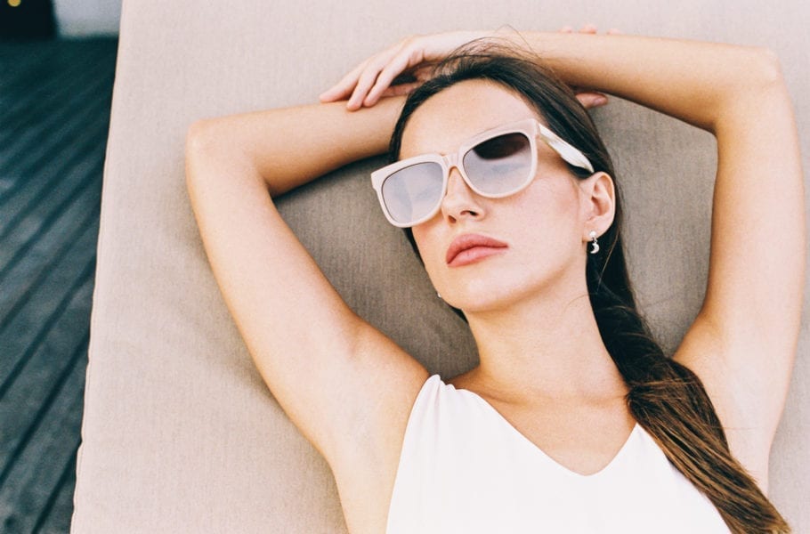 Overhead shot of a woman relaxing on a sunbed with sunglasses.