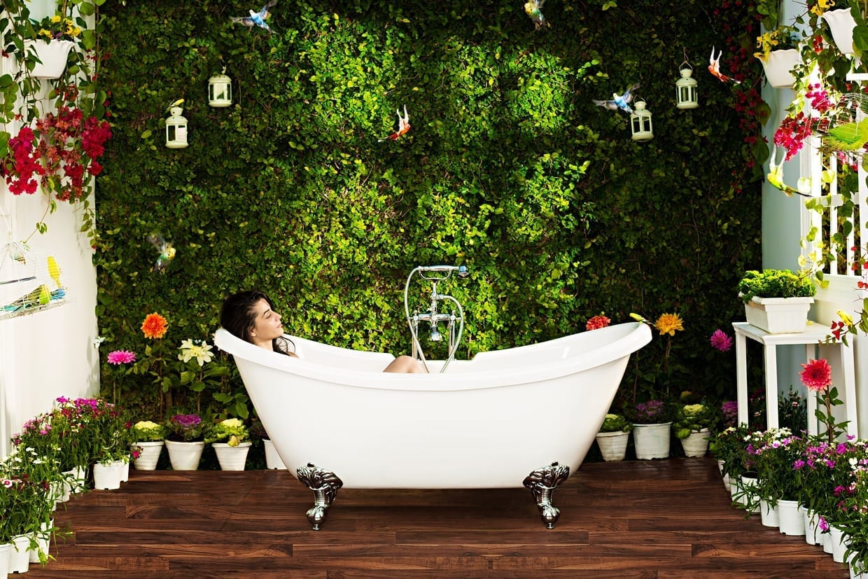 A woman in a tub surrounded by plants.