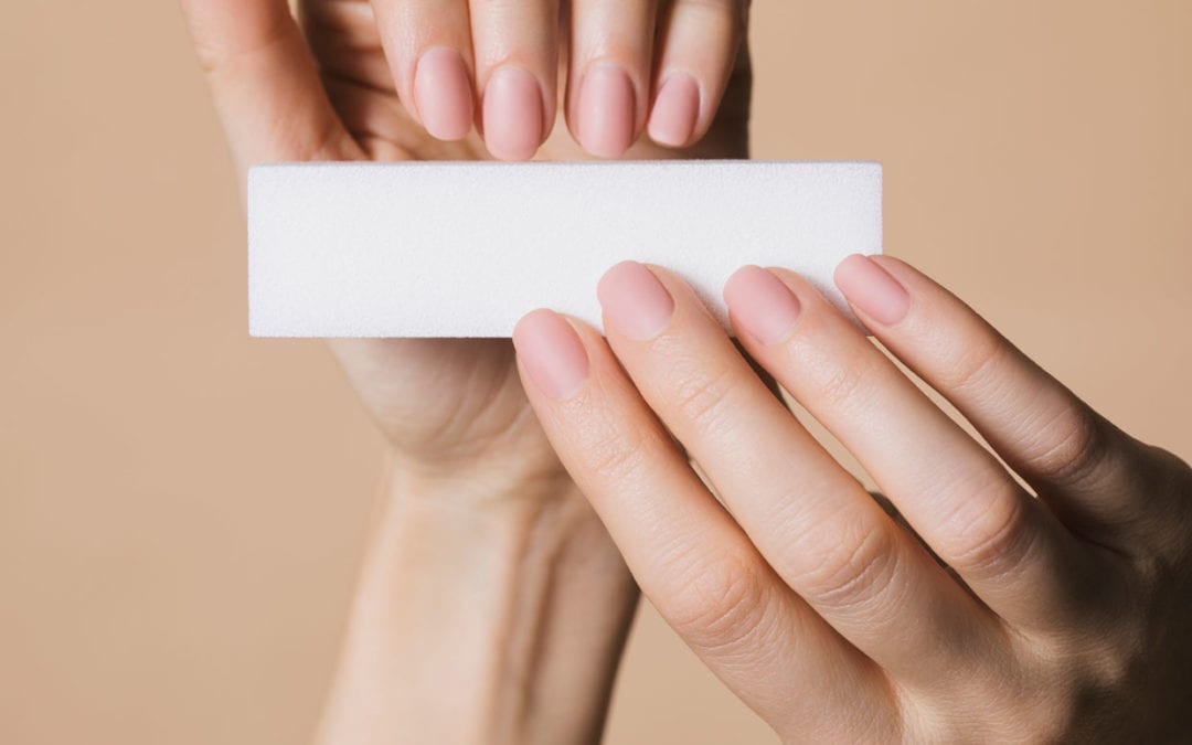 Hands of unrecognizable woman using nail file for manicure.