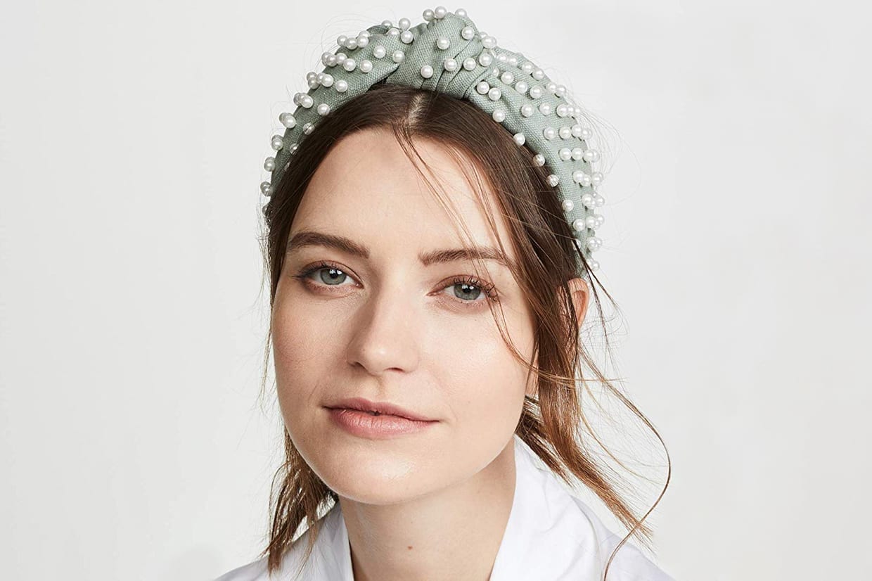 A woman wearing a light blue headband with pearls.