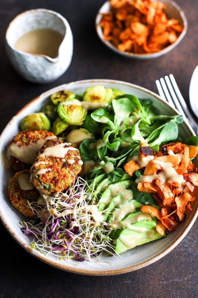 A bowl of spinach bites, avocado, and greens.
