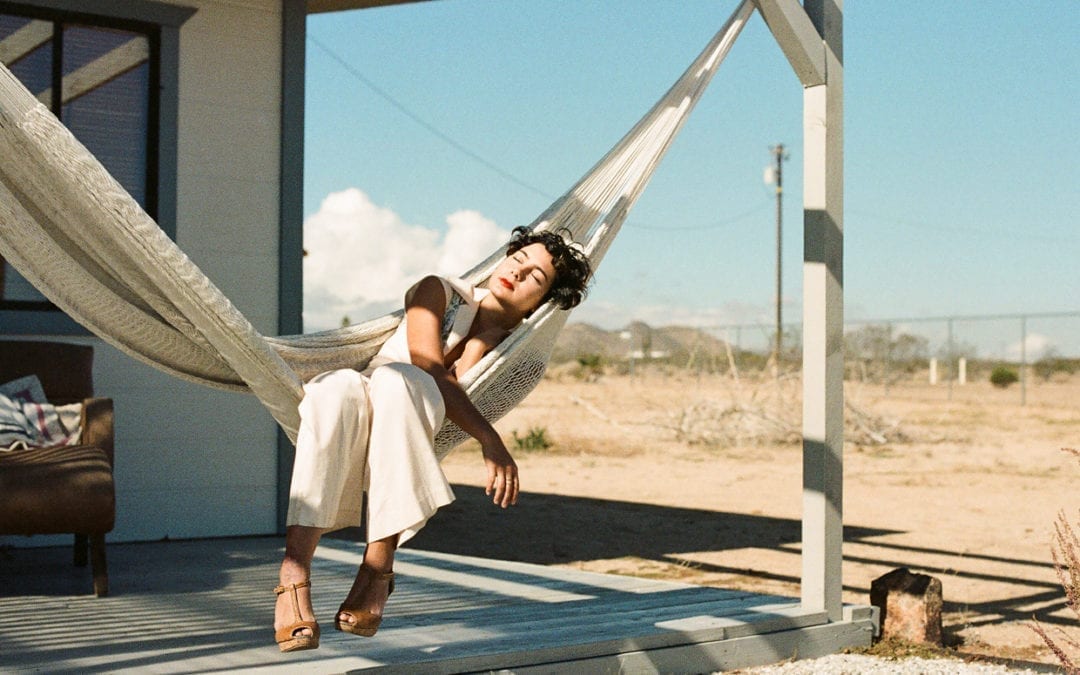 A woman resting on a hammock on a porch.