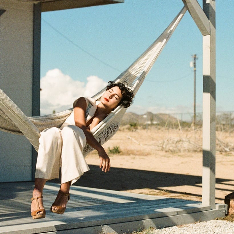 A woman resting on a hammock on a porch.
