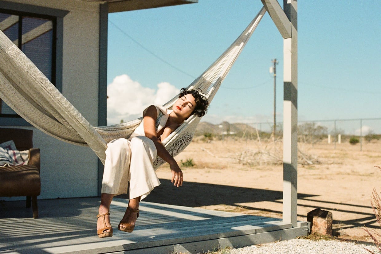 A woman resting on a hammock on a porch.