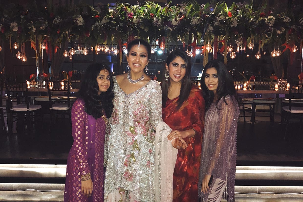 Four women in saris at a wedding.