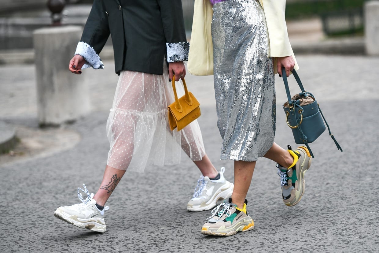 Two women walking wearing dresses and sneakers.