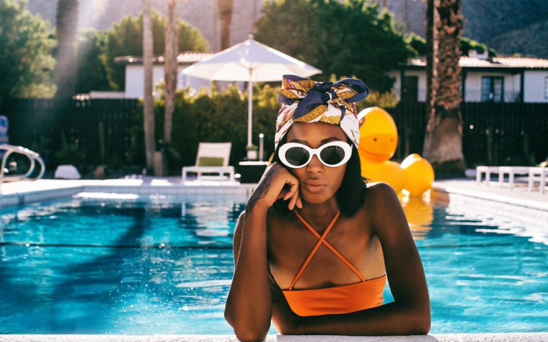 A young woman poses in the pool of a stylish resort.