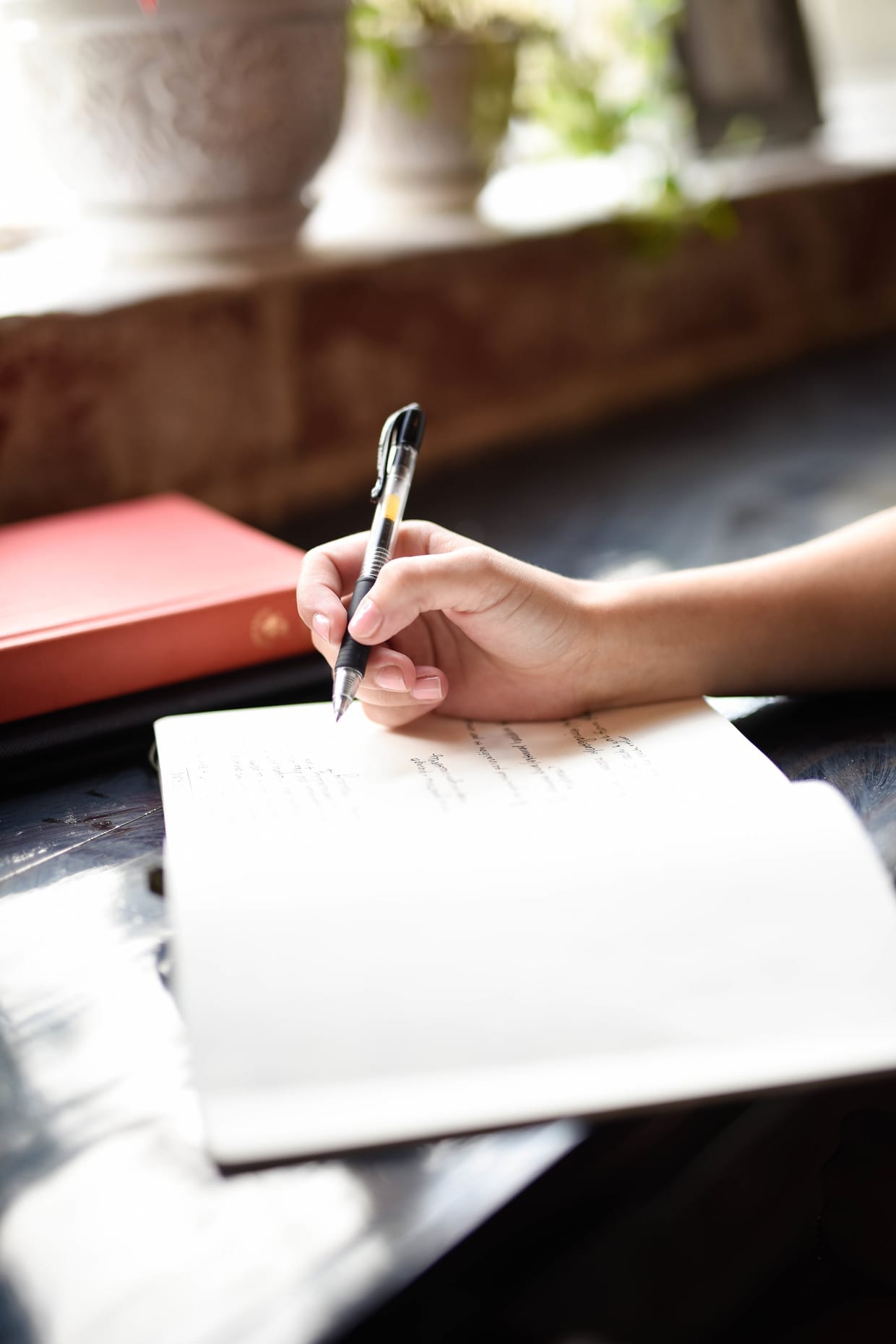 A woman's hand holds a pen on a notebook.