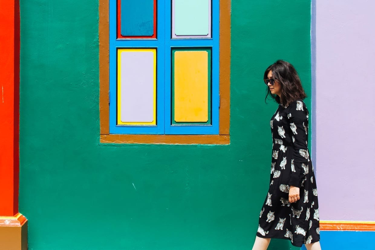 A woman wearing long black dress walks past a colourful wall of the Tan Teng Niah house in Little India, Singapore.
