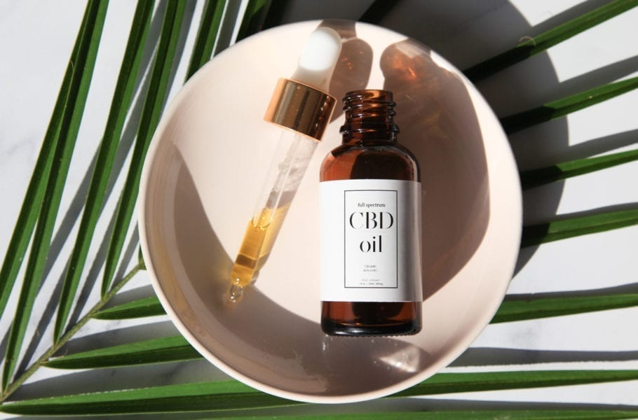 CBD Oil bottle and dropper on small plate and on marble surface.