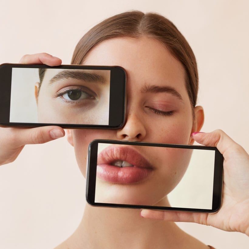 Conceptual shot of young woman's eye and lips being covered with exaggerated ones on smartphone screens.