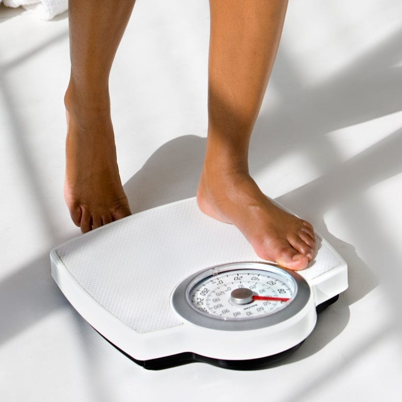 A woman steps on a scale.