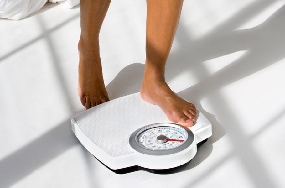 A woman steps on a scale.