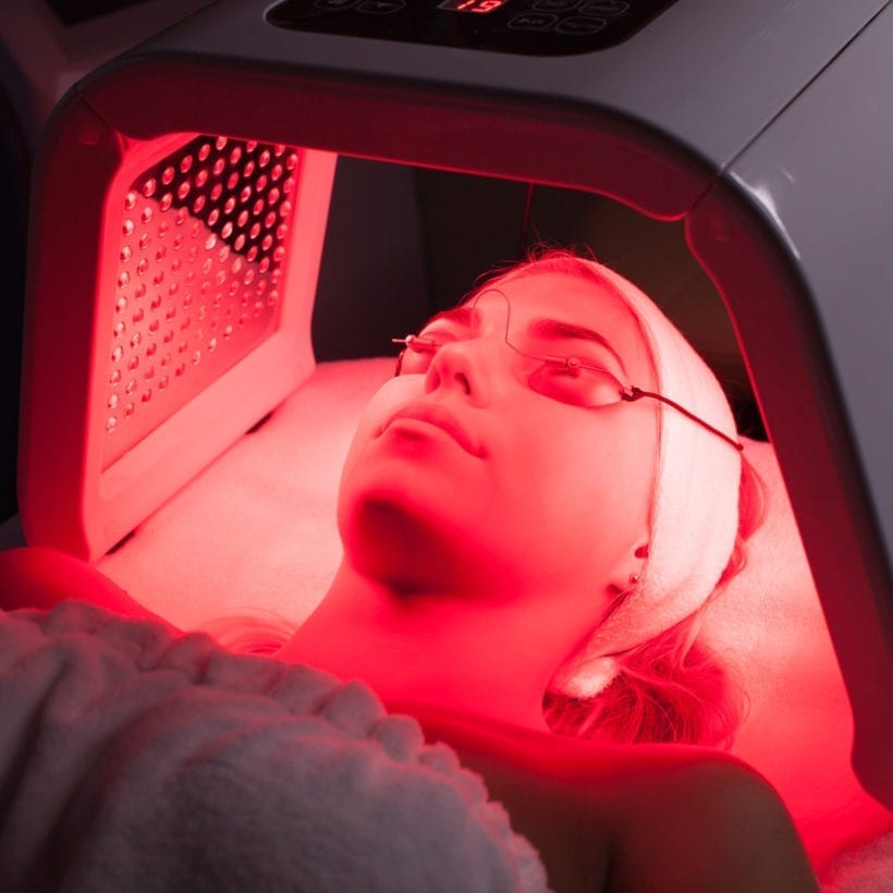 Young woman having an LED light facial treatment.