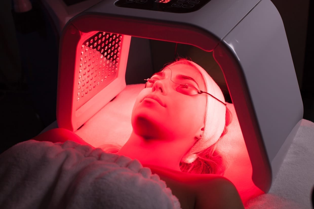 Young woman having an LED light facial treatment.