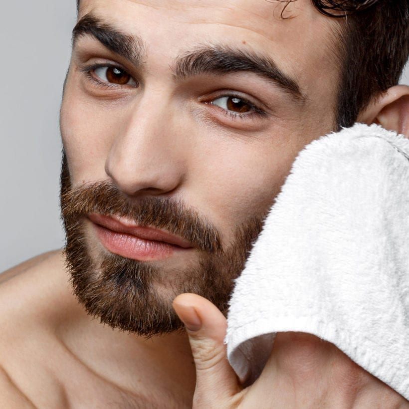 A man wipes his face with a towel.