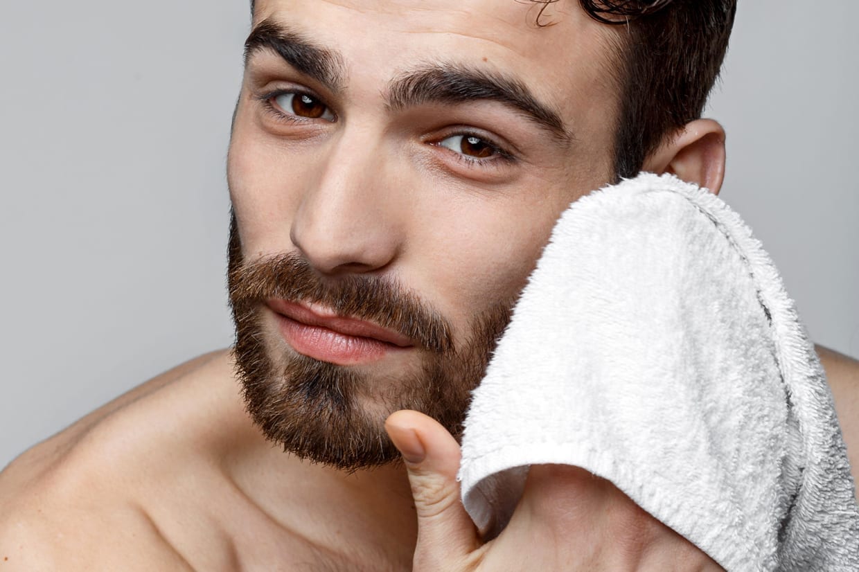 A man wipes his face with a towel.