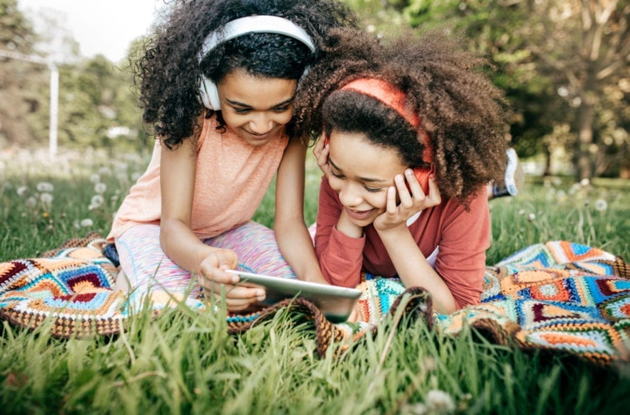Two girls with headphones looking at an iPad.