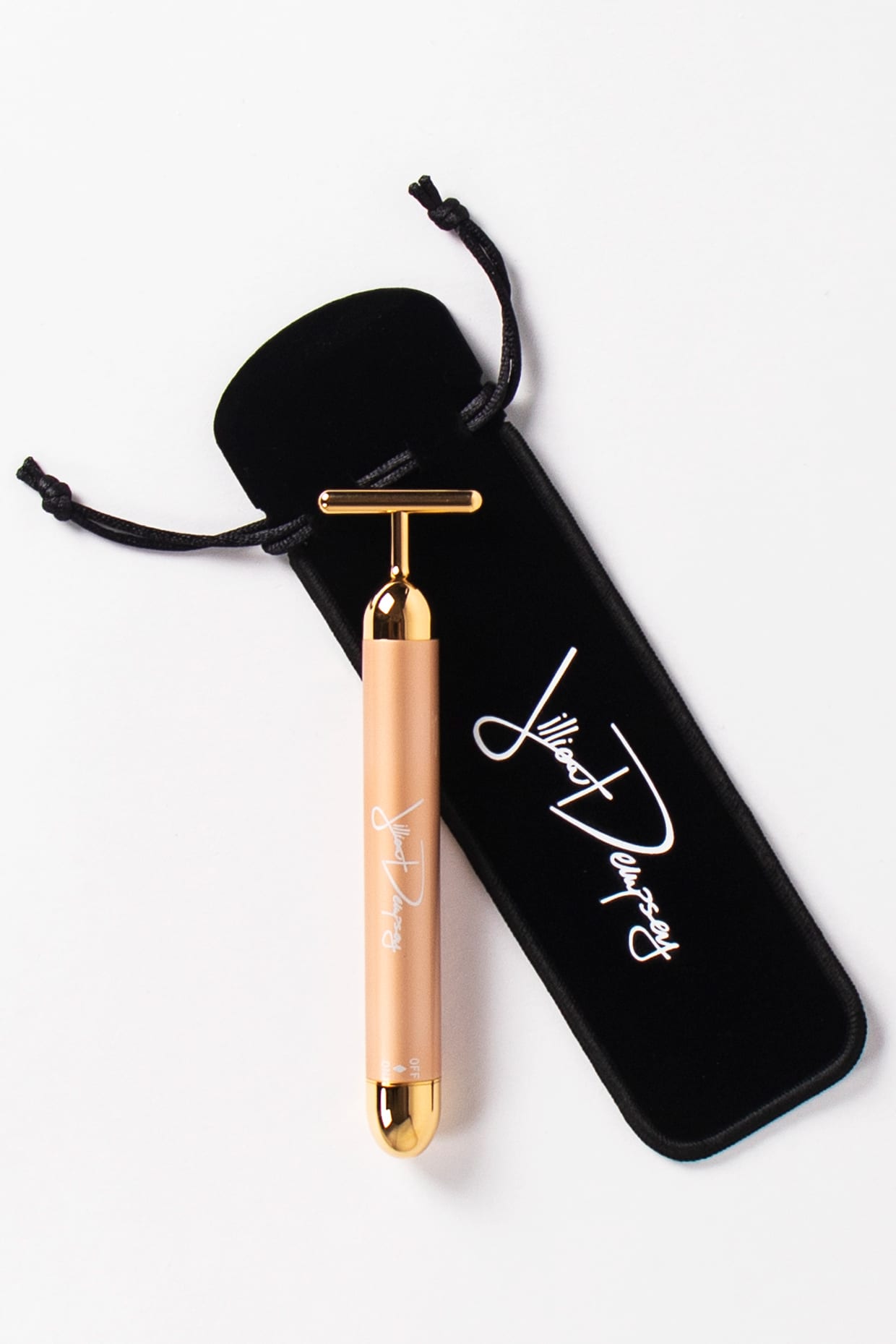 A T-shaped 24K gold bar and black velvet bag on white.