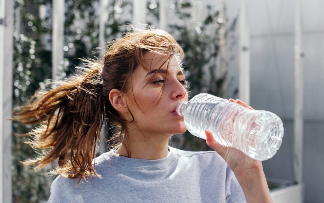 A woman drinking water from a bottle.