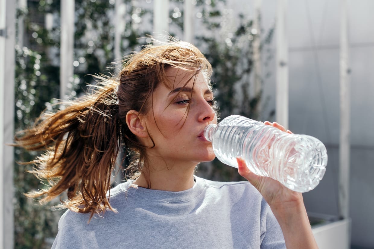 A woman drinking water from a bottle.