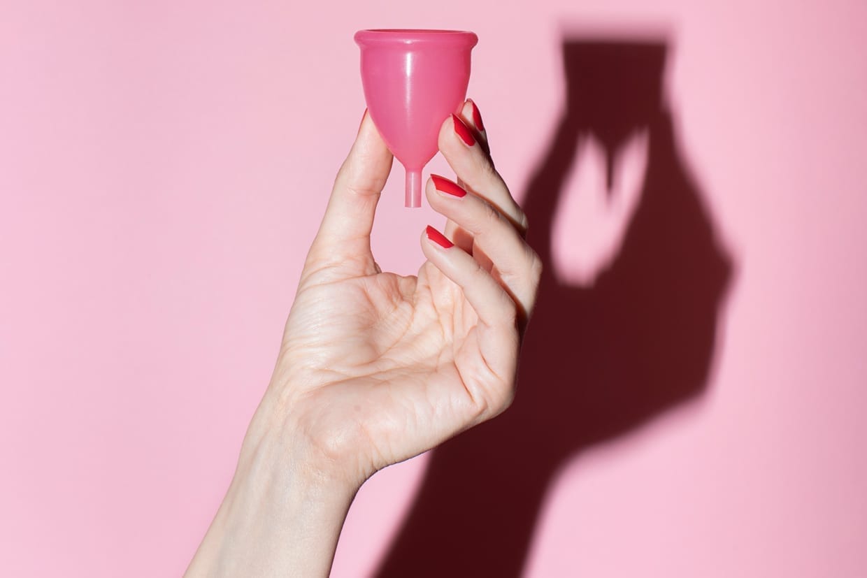 A woman's hand holding a menstrual cup.