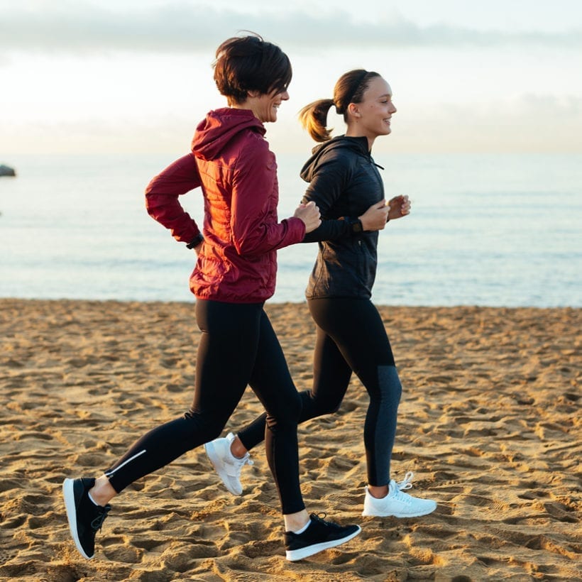 A mother and daughter running on the beach.