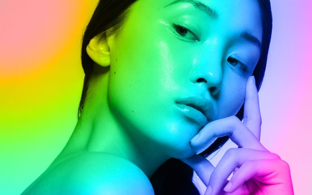 An asian woman with a rainbow gradient overlay.
